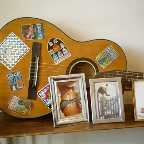 Detailaufnahme mit akustischer Gitarre und Urlaubs-Fotos
