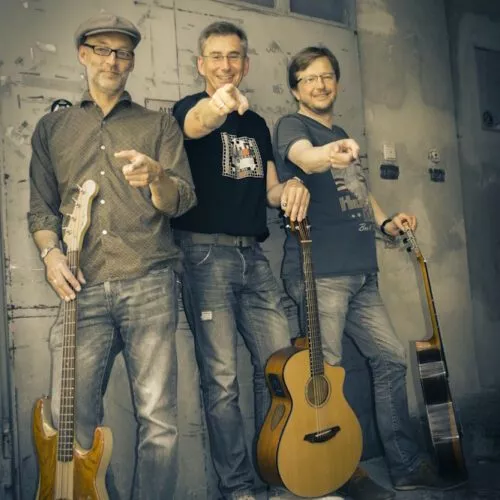 Träumer Band-Foto: Die drei Musiker mit Gitarren vor einem Eisentor
